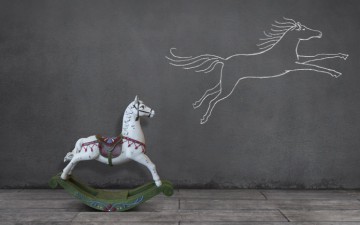 Image of a rocking horse looking at a drawing of a horse flying