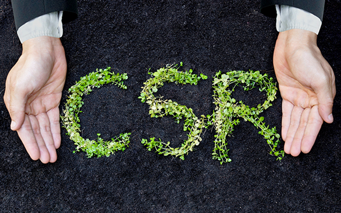 Hands of a businessman holding green plants arranged as a word "CSR"