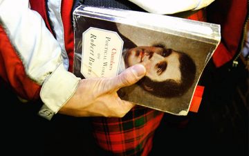 Image of a person holding a collection of poetry by Robert Burns